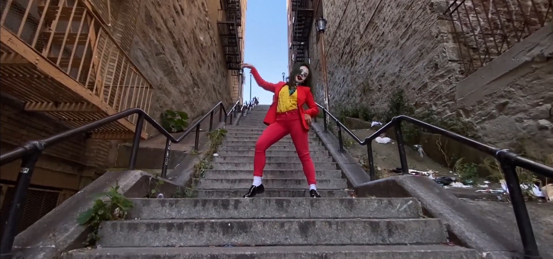A fan in the Joker's red suit dancing on the Joker stairs in the Bronx